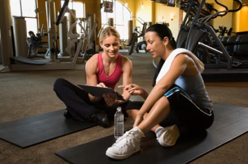 Adult female with personal trainer at gym.